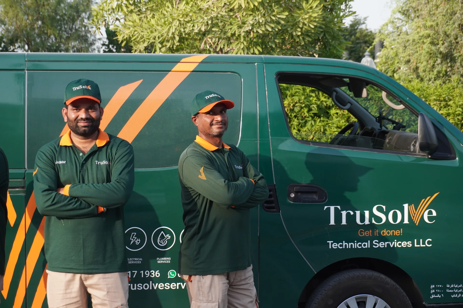 Two TruSolve villa maintenance technicians beside the branded service van